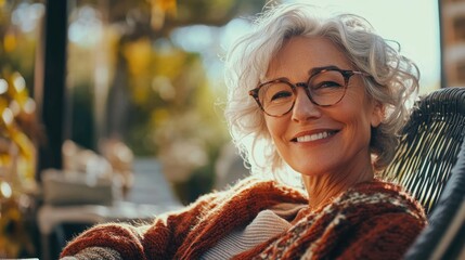 A woman sits in a chair wearing glasses, looking straight ahead