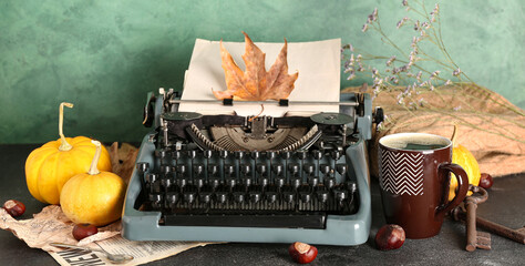 Vintage typewriter, pumpkins, chestnuts, cup of coffee and autumn leaves on table