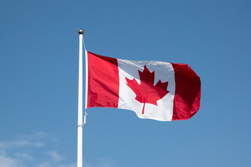 canadian flag waving against blue sky
