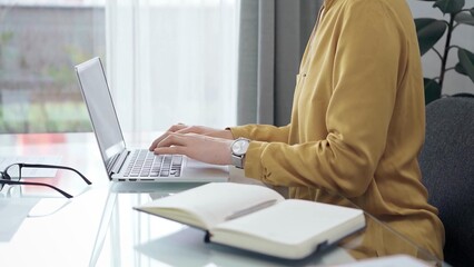 Young professional woman is working with laptop in modern office. Yellow blouse is passing to adult businesswoman. Flying to success concept