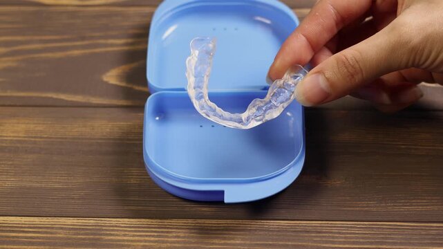 Woman puts a protective mouthguard for teeth in a box.