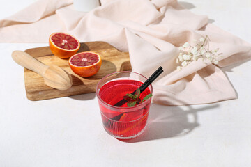 Glass of tasty blood orange lemonade on light background