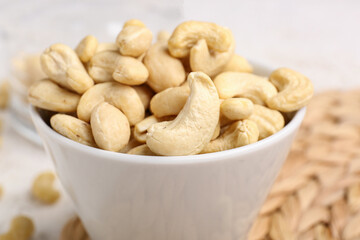 Bowl with tasty cashew nuts on table, closeup