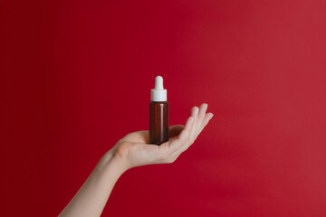 Serum glass unbranded bottle (essential oil) with pipette on red background. Natural moisturizing, nourishing cosmetics for skin, beauty and spa