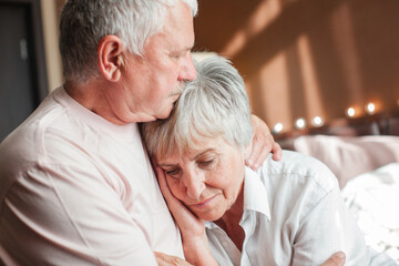 Worried senior woman embracing upset old man