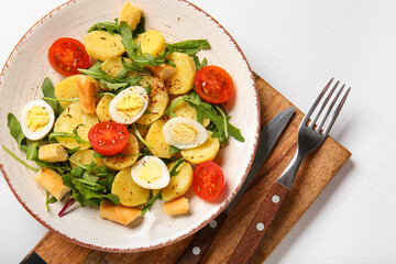 Plate of tasty potato salad with eggs and tomatoes on white background, top view