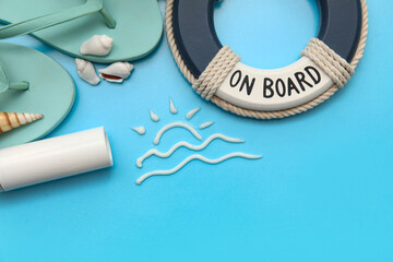 Composition with sun made of sunscreen cream, ring buoy, flip-flops and seashells on blue background