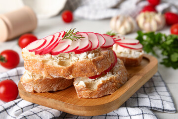 Board with delicious radish bruschettas on table, closeup