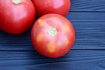 pile of red round fresh tomatoes lie on black wooden table