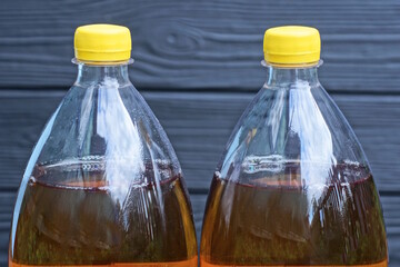 two plastic bottles with yellow lemonade drink near black wall