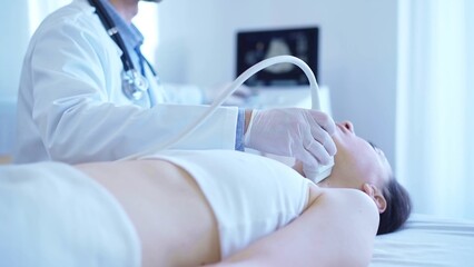 Naklejka premium Doctor man with white medical gloves is using ultrasound machine to examine neck of female patient lying down in clinic. Medicine concept