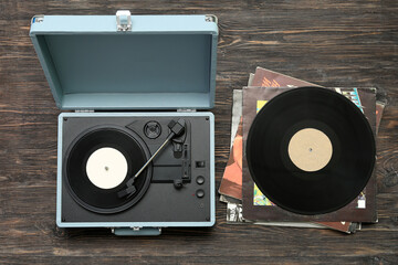 Record player with vinyl disks on dark wooden background