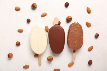 Composition with different chocolate covered ice cream and nuts on white table