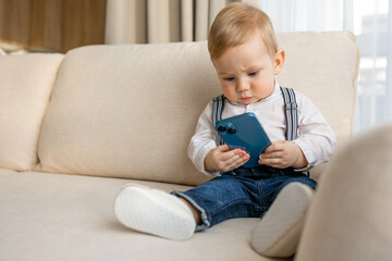 Fototapeta premium Cute Baby Boy Using Smartphone on Couch at Home