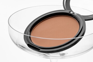 Beige makeup compact powder for face in a cocktail glass, product presentation