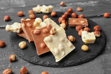 Different tasty chocolate with nuts on  dark wooden background