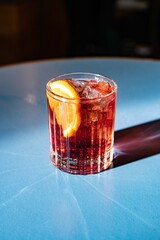 A fresh negroni on a blue table in the sun
