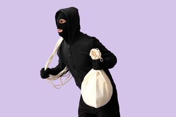 Male thief with bag and rope on lilac background