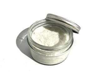 A glass jar of refined salt with silver twist lid isolated on white background