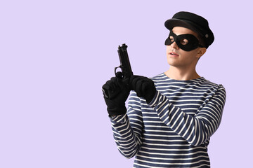 Male thief with gun on lilac background