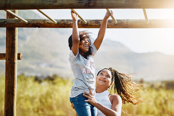 Mother, happy child and play at jungle gym for support, energy or exercise with family at park. African mom, girl and kid at playground or climbing on monkey bar for health, help or laugh with parent