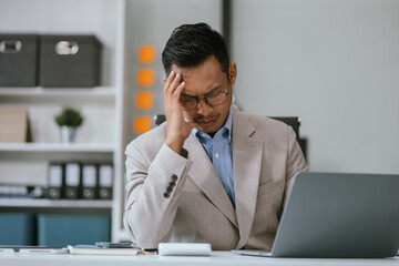 Stressed businessman calculating bills and taxes looking at calculator gesturing with hands sitting at work desk. Selective Focus