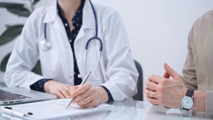 Doctor and patient are talking in clinic after health check up. Female physician is making notes. Medicine concept