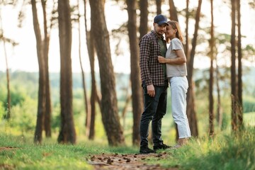 Lovely couple are together in the forest at summer daytime