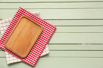 Table setting with board and napkins on green wooden background