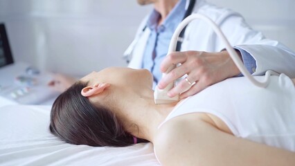 Fototapeta premium Doctor man is using ultrasound equipment on neck of female patient lying down for a medical examination. Medicine and science