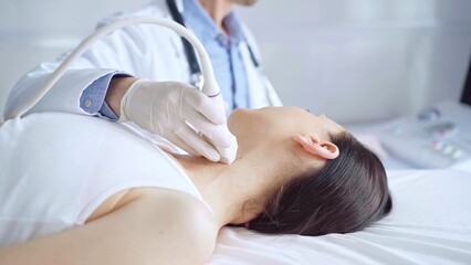 Doctor man is using ultrasound equipment on neck of female patient lying down for a medical examination. Medicine and science