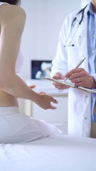 Doctor and patient. Physician is making notes on a clipboard while patient woman is describing something. Pediatrician, medicine concept