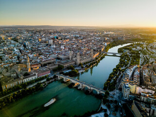 Obraz premium Spectacular Zaragoza city skyline at sunset. View of old town center, Cathedral of Zaragoza and Ebro River. Medieval and historic travel destination in Aragon - Spain. Sunset point, orange reflections