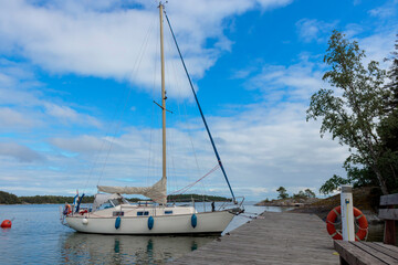 Sailboat at the harbor of the island tied to a mooring buoy in Finland, Baltic sea, traditional sail yacht in shore marina in Baltic sea, summer vacations in archipelago
