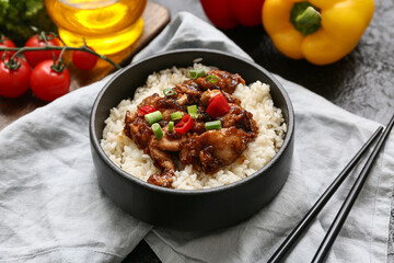 Tasty sweet and sour chicken with rice in bowl, napkin and chopsticks, closeup