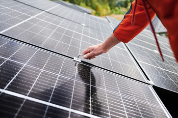 Man worker mounting photovoltaic solar panels on roof of house. Close up view of engineer...