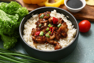 Tasty sweet and sour chicken with rice in bowl and vegetables on turquoise grunge background, closeup