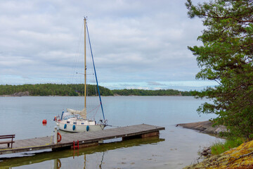 Sailboat at the harbor of the island tied to a mooring buoy in Finland, Baltic sea, traditional sail yacht in shore marina in Baltic sea, summer vacations in archipelago