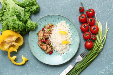 Tasty sweet and sour chicken with rice in plate, vegetables and fork on turquoise grunge background
