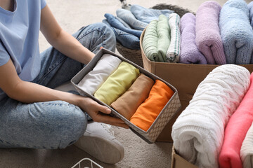 Obraz premium Young woman folding clean clothes into different organizers at home, closeup