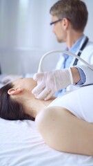 Doctor man wearing white protective gloves is using ultrasound equipment on the neck of patient woman, lying for examination. Medicine concept