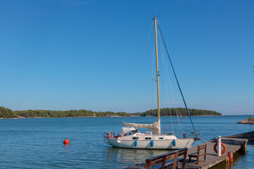 Sailboat tied to a mooring buoy at the harbor of the island in Finland, Baltic sea, Yacht in Shore...