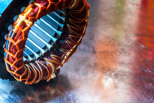 Electric motor stator with winding coil on metal surface of workshop table, close-up view