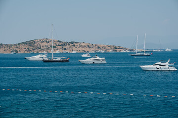 A scenic view of luxurious marine boats and yachts anchored by the coastline, displaying the...