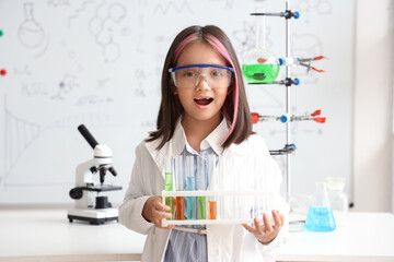 Cute little girl holding test tubes with colorful liquids in chemistry classroom