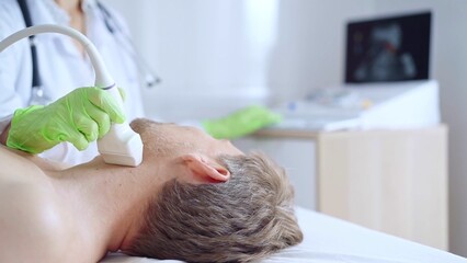 Doctor woman with green medical gloves performing neck ultrasound exam on male patient. Thyroid...