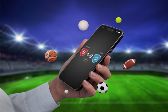 Phone in hand with a live score app displayed on the screen, set against a football stadium backdrop. Sports balls are flying around the phone, emphasizing real-time updates and sports excitement