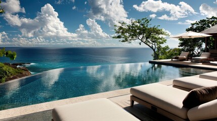 Fototapeta premium A tranquil infinity pool reflects clouds and blue sea at a tropical resort