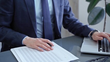 Businessman analyzing financial data on laptop and calculator. Close-up of a professional auditor working on financial reports. Business concept