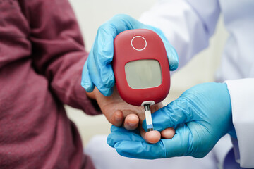 Asian doctor using digital glucose meter for check sample blood sugar level to treatment diabetes.